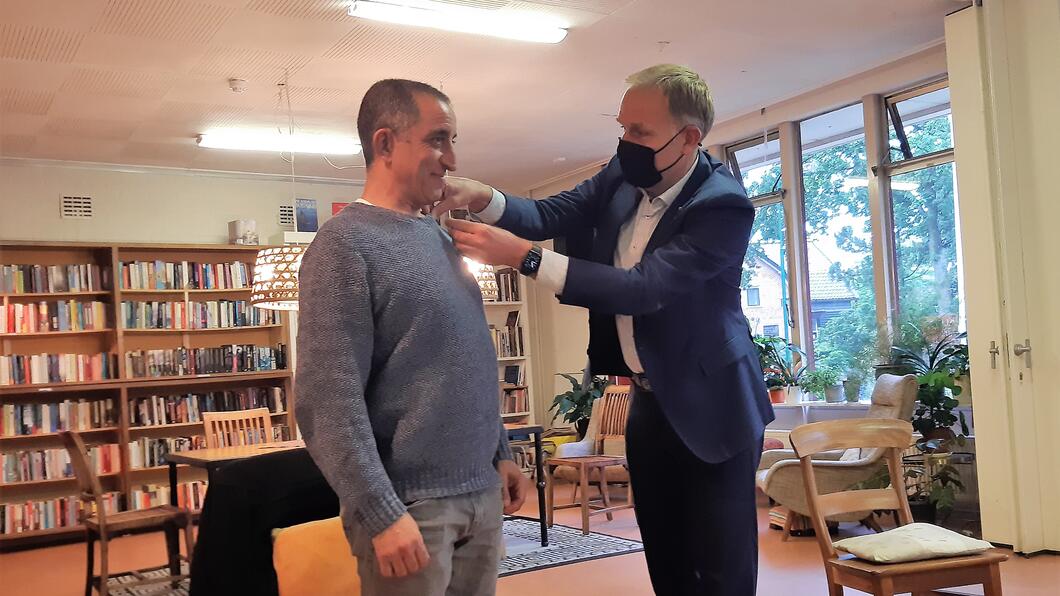 Huib van Essen speldt het Groene Lintje op bij Allal Ennahachi.