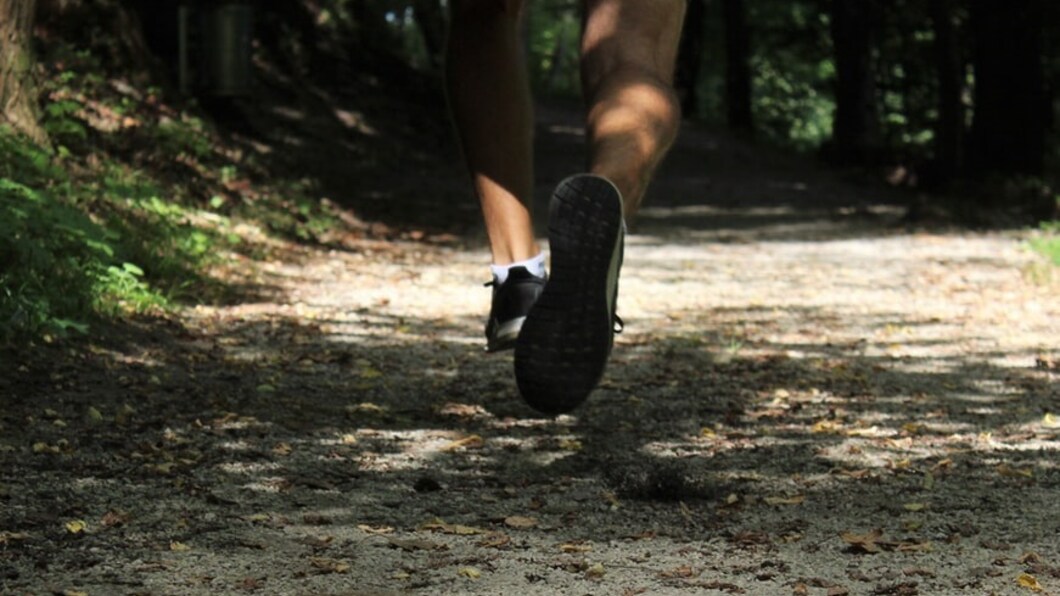 Man die door het bos rent op sportschoenen.