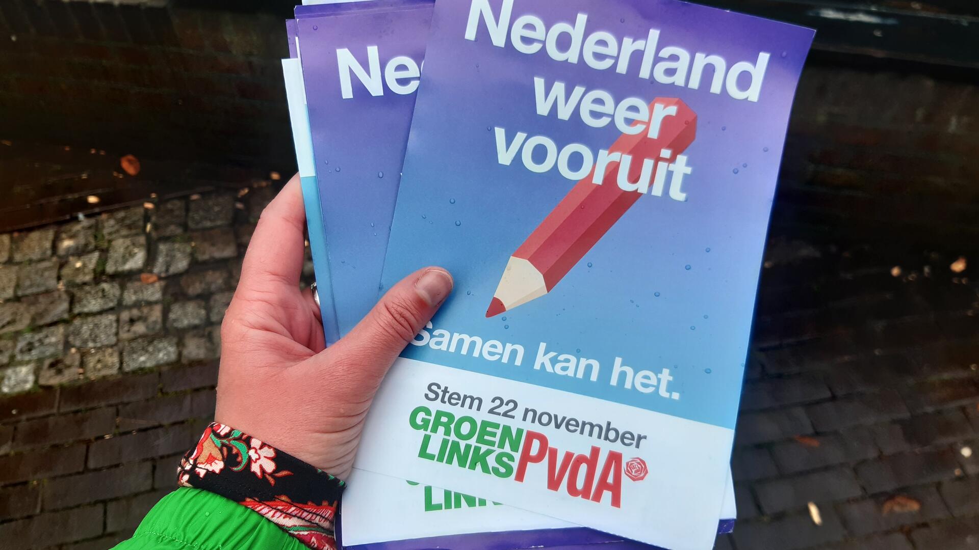 Hand met daarin de flyer van GroenLinks-Pvda met de tekst 'Nederland weer vooruit'.